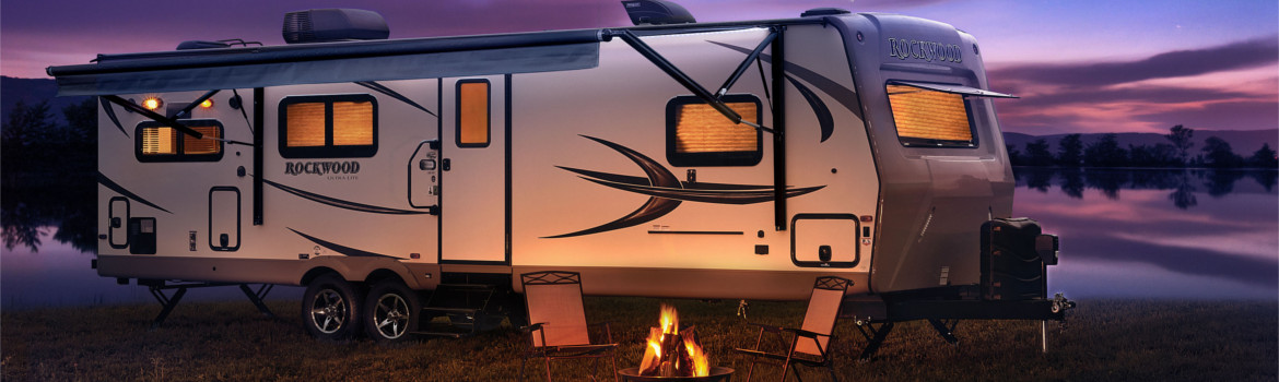 A white 2019 Forest River RV Rockwood parked in front of a lake.